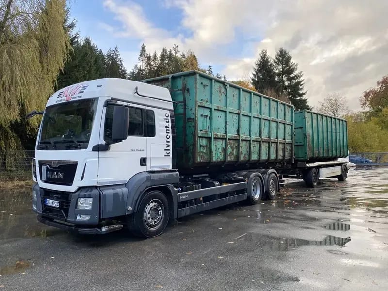 Abrollcontainer-Fahrzeug mit grünen Containern