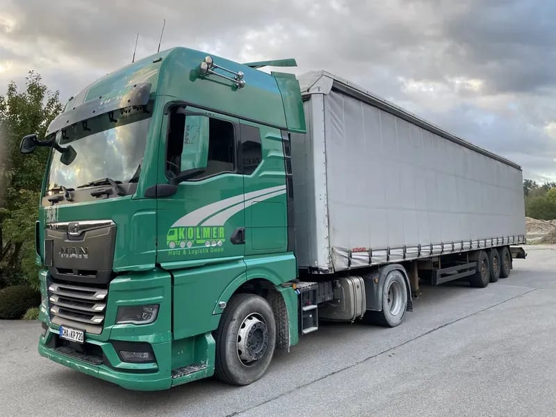 Grüner Kolmer-Planensattelzug mit Curtainsider-Auflieger auf dem Betriebsgelände